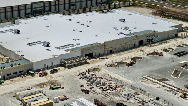 Aerial view of the large industrial warehouse construction site at Foundry Lane featuring a white flat roof and heavy machinery World Golf Village, Florida, United States.