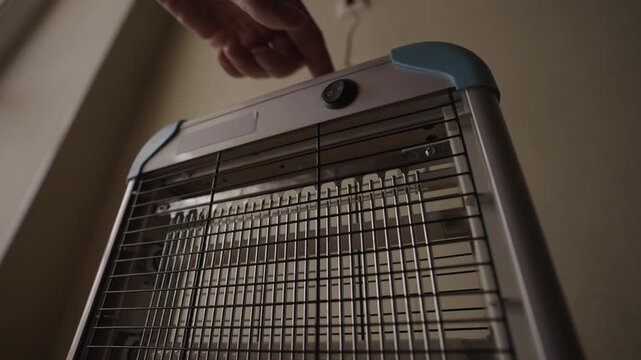 Low-angle view of electric insect killer lamp switches on, glowing with bright blue UV light to attract and eliminate pests. Device powers down. Pest control equipment in action, slow motion.