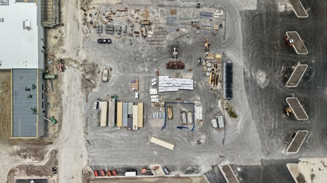 Aerial view of the Foundry Lane construction site with shipping containers, building materials, and heavy machinery in World Golf Village, Florida, United States.