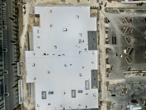 Aerial view of a large commercial building under construction on Foundry Lane with a white flat roof and surrounding parking lot layout in World Golf Village, Florida, United States.