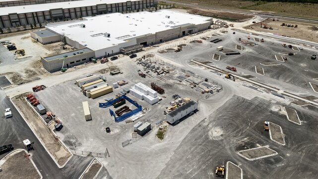 Aerial view of the construction site at Foundry Lane featuring large industrial buildings, heavy machinery, and building materials in World Golf Village, Florida, United States.
