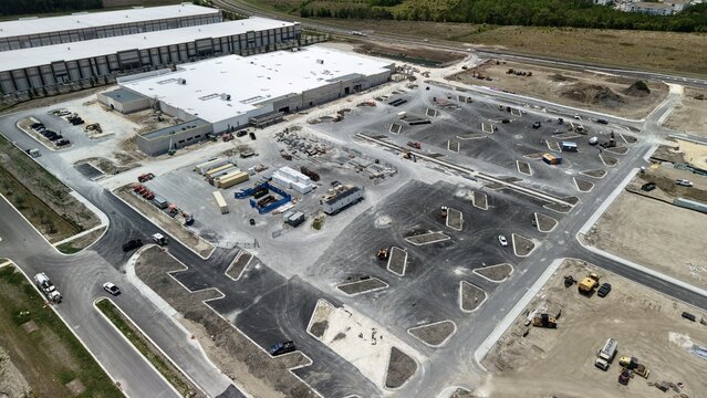Aerial view of Foundry Lane construction site featuring large industrial warehouses and a developing parking lot with heavy machinery in World Golf Village, Florida, United States.