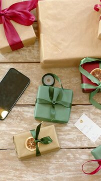 Vertical video: Panning camera revealing wrapped gifts on wooden tabletop, with ribbon phone tag