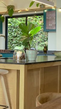 Vertical video: Panning camera across kitchen island, showing faucet, decor and window garden