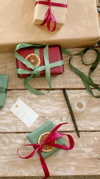 Vertical video: Filming camera panning on tabletop, showing final wrapped gift arrangement, ribbon