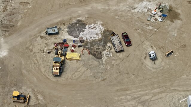 Aerial view of Foundry Lane construction site with heavy machinery, a grader, a bulldozer, and workers on the dusty ground in World Golf Village, Florida, United States.