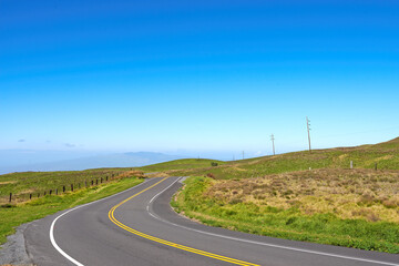 Obraz premium Empty, blue sky and road in countryside for travel, tourist destination and journey outdoor. Landscape, background and street with scenic route, highway or mockup space for vacation, trip and holiday