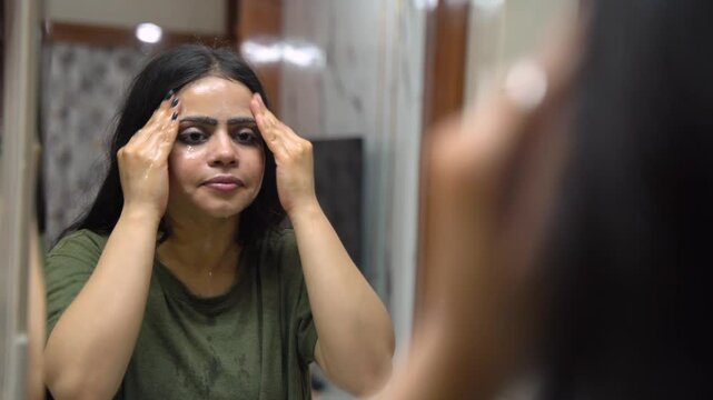 Indian Woman Applying Face Wash Cleanser on Face in Bathroom at Home