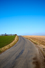 Obraz premium Landscape, blue sky and road in countryside for travel, tourist destination and journey outdoor. Empty, background and street with scenic route, highway and space for vacation, trip and holiday