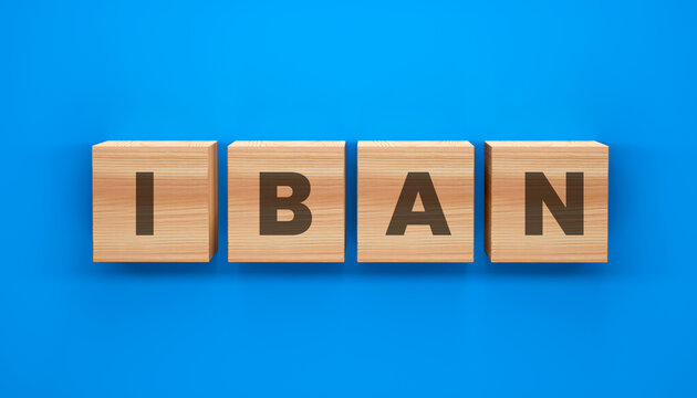 IBAN Wood Block: A close-up shot of wooden blocks spelling out the acronym IBAN against a vibrant blue backdrop, signifying the essential building blocks of international banking transactions.