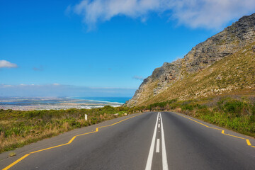 Obraz premium Landscape, blue sky and road on mountain for travel, tourist destination or journey to ocean. Empty, background and street with scenic route, highway and nature for vacation, trip or holiday by coast
