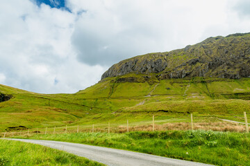 Obraz premium Gleniff Horseshoe in County Sligo, Ireland, with rolling grassland beneath steep limestone mountains and bright clouds. A scenic drive through one of Irelands classic valleys.