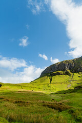 Obraz premium Gleniff Horseshoe in County Sligo, Ireland, with rolling grassland beneath steep limestone mountains and bright clouds. A scenic drive through one of Irelands classic valleys.