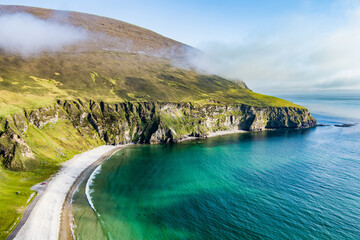 Naklejka premium Aerial view of the southern end of Keel Beach on Achill Island, County Mayo, Ireland. White pebbles, turquoise water and steep cliffs define this rugged Atlantic cove.