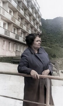 Vintage portrait of a beautiful elderly woman with a hairstyle against the background of mountains and a boarding house building in Tskaltubo, Georgia, 1956