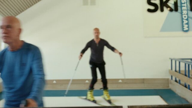 Senior adult man training on an indoor ski simulator with his coach on a rolling carpet
