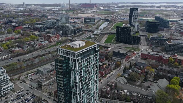 Modern Toronto building with green rooftop over urban landscape, featuring Gardiner Expressway traffic, Port Lands industrial area and Don River in Ontario, Canada