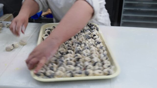 Asian Cook Arranging Large Dumpling Tray On Prep Table, Industrial Kitchen Setting With Rows Of Filled Pieces, Rapid Hands Placing Items Into