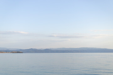Fototapeta premium Calm Serene Seascape with Distant Mountains and Clear Blue Sky