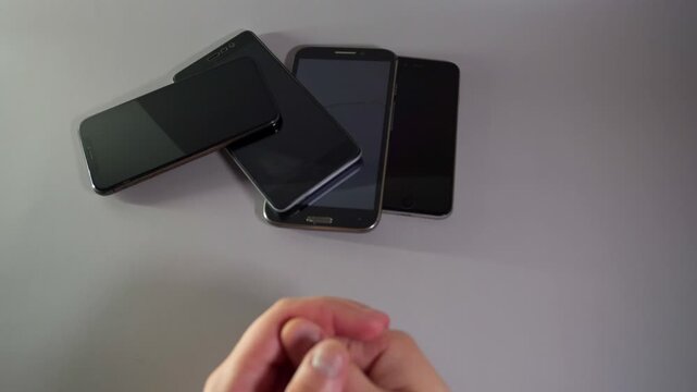 Close-Up Hands Holding Stack of Smartphones and Dealing Them One by One