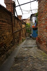 Wąska uliczka w starym Tbilisi otoczona jest tradycyjnymi domami z charakterystyczną lokalną architekturą i drewnianymi balkonami. Klimatyczny zaułek oddaje historyczny charakter miasta. © Adam
