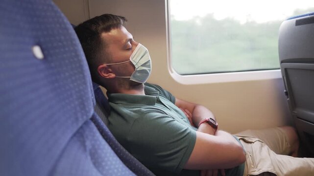 Tired sleeping train commuter wearing PPE face mask for safety. Concept travel during pandemic. Protective medical mask during the trip. Medical respiratory bandage face in transport.