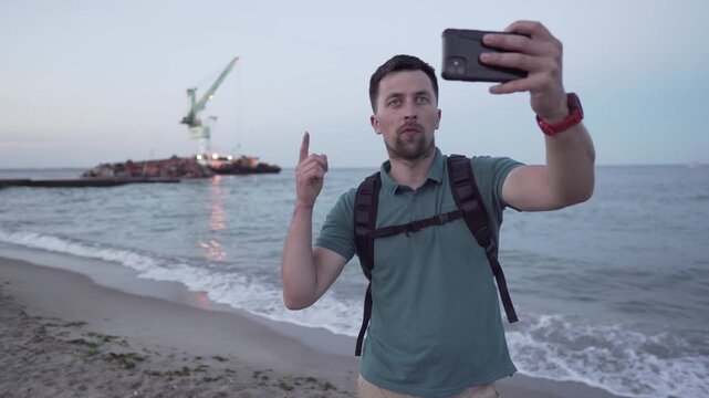 Human journalist make report on sunken tanker Delfi in Odessa. Male blogger shoots video on phone, publish post about ship wreck in Black Sea. Man video blogger tell subscriptions about boat accident.