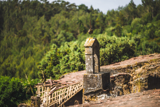Minimal composition with a tiny old stone bell tower at frame edge, blurred green woodland beyond, and ample negative space for peaceful heritage themes