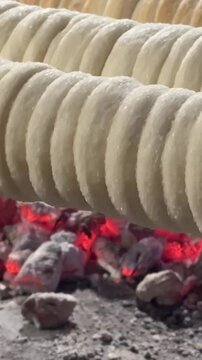 Kurtos chimney cake preparation Hungarian Czech sweet dough rolled over spit traditional baked dessert street food