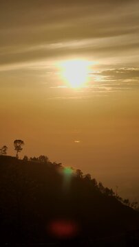 Vertical Video Sunrise Silhouette over Mount Merapi with Sunrise Mountain View, Sunrise Morning Light, Mount Merapi Landscape, Golden Sun in Frame and Serene Vacation Concept.
