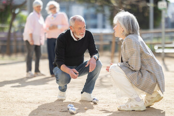 Obraz premium Focused elderly people analyzing results of petanca game while spending leisure time outdoors