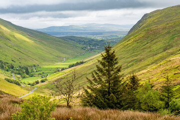 Obraz premium Glengesh Pass winding through a green mountain valley in County Donegal, Ireland. A scenic road landscape of the Wild Atlantic Way and remote Irish highlands.