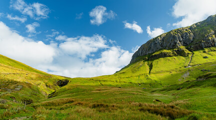 Obraz premium Gleniff Horseshoe in County Sligo, Ireland, with rolling grassland beneath steep limestone mountains and bright clouds. A scenic drive through one of Irelands classic valleys.