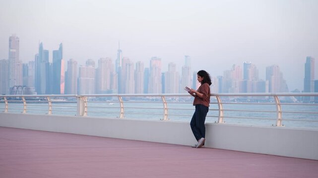 Female reader enjoying calm outdoor lifestyle beside Dubai skyline waterfront footage