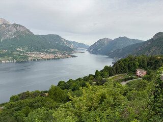 Fototapeta premium Lake como extending between mountains with bellagio town visible on the shore, lush green trees and hillside buildings adding to the stunning destination vista under an overcast sky