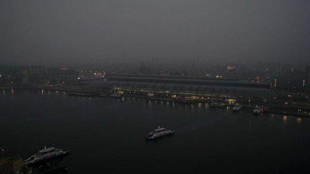 Aerial view of a ferry sailing on the IJ river with Amsterdam Centraal station in the background