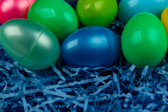 Colorful plastic Easter eggs on blue paper grass