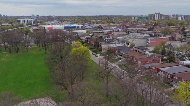 Bird's eye capturing urban park, suburban houses, Walmart, distant cityscape on an overcast day, revealing a unique blend of nature and city development in North America