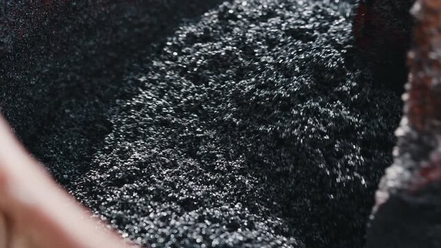 Mixing recycled rubber granules for surface coating preparation close up