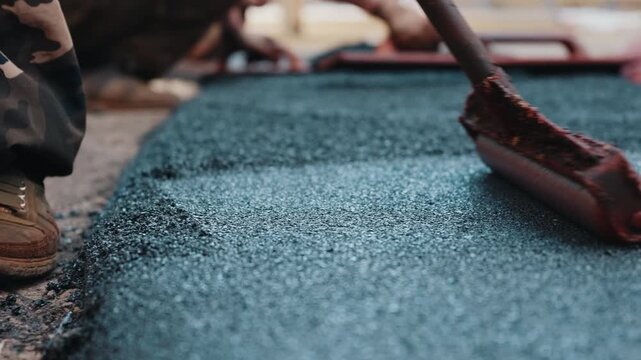 Leveling rubber crumb coating on playground surface during installation close up