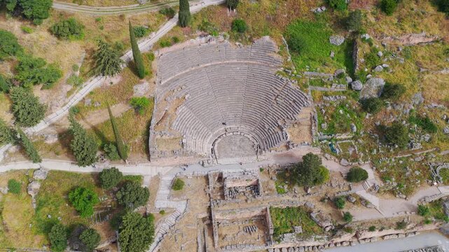 Top-down aerial view slowly rotating over the ancient theatre of Delphi, a famous archaeological site and Unesco world heritage monument located in the mountains of Greece on a sunny day