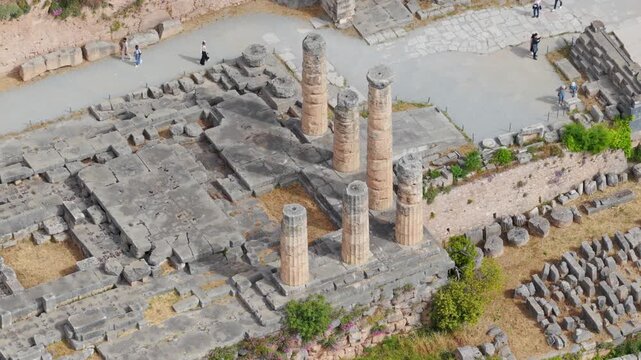 Aerial perspective of the ancient ruins of the temple of Apollo in Delphi, Greece, a famous archaeological site and historical landmark where tourists are exploring the ancient greek civilization