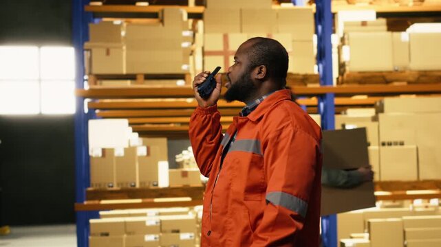 African american worker transmitting information via walkie-talkie radio signal, internal depot communication to ensure express delivery and quality operations. Distribution hub.
