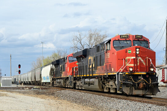 Two Canadian National Railway locomotives lead a manifest freight train through a diamond crossing with another railroad in suburban Chicago.