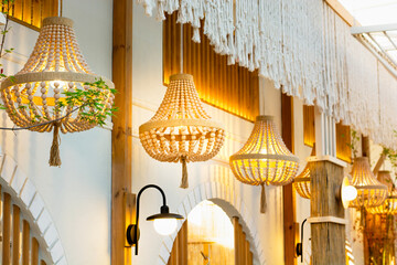 Beautiful wooden bead chandeliers hanging in a stylish boho cafe interior with warm lighting. High quality photo © Anna