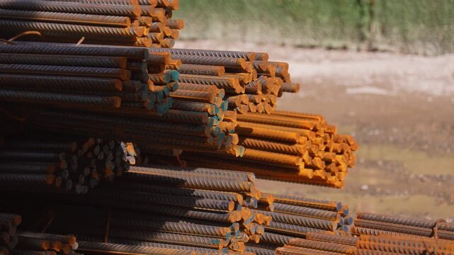 Bundles of rusted reinforcing steel bars, known as rebar, are stacked at a construction site, essential material for reinforcing concrete and building strong structures in the industry