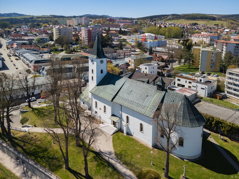 Aerial view of the Roman Catholic Church of Saints Simon and Jude with its white facade and black spire overlooking the town buildings Namestovo, Zilina Region, Slovakia.