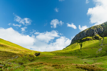 Obraz premium Gleniff Horseshoe in County Sligo, Ireland, with rolling grassland beneath steep limestone mountains and bright clouds. A scenic drive through one of Irelands classic valleys.