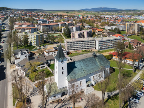 Aerial view of the Roman Catholic Church of Saints Simon and Jude with its white tower and green roof, surrounded by urban buildings and green trees, Namestovo, Zilina Region, Slovakia.