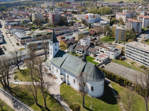 Aerial view of the Roman Catholic Church of Saints Simon and Jude with its white walls and green roof surrounded by trees and urban buildings in Namestovo, Zilina Region, Slovakia.